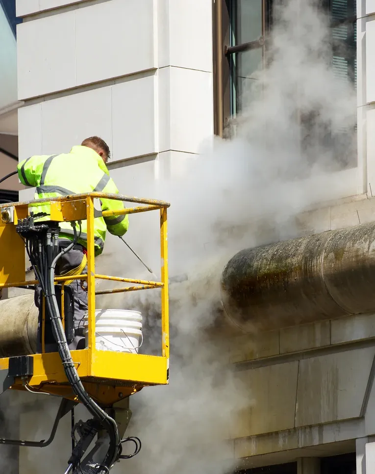 A man cleaning a commercial building facade with a pressure washer
