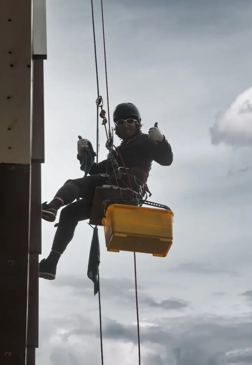 A man window cleaning the outside of a large building and smiling