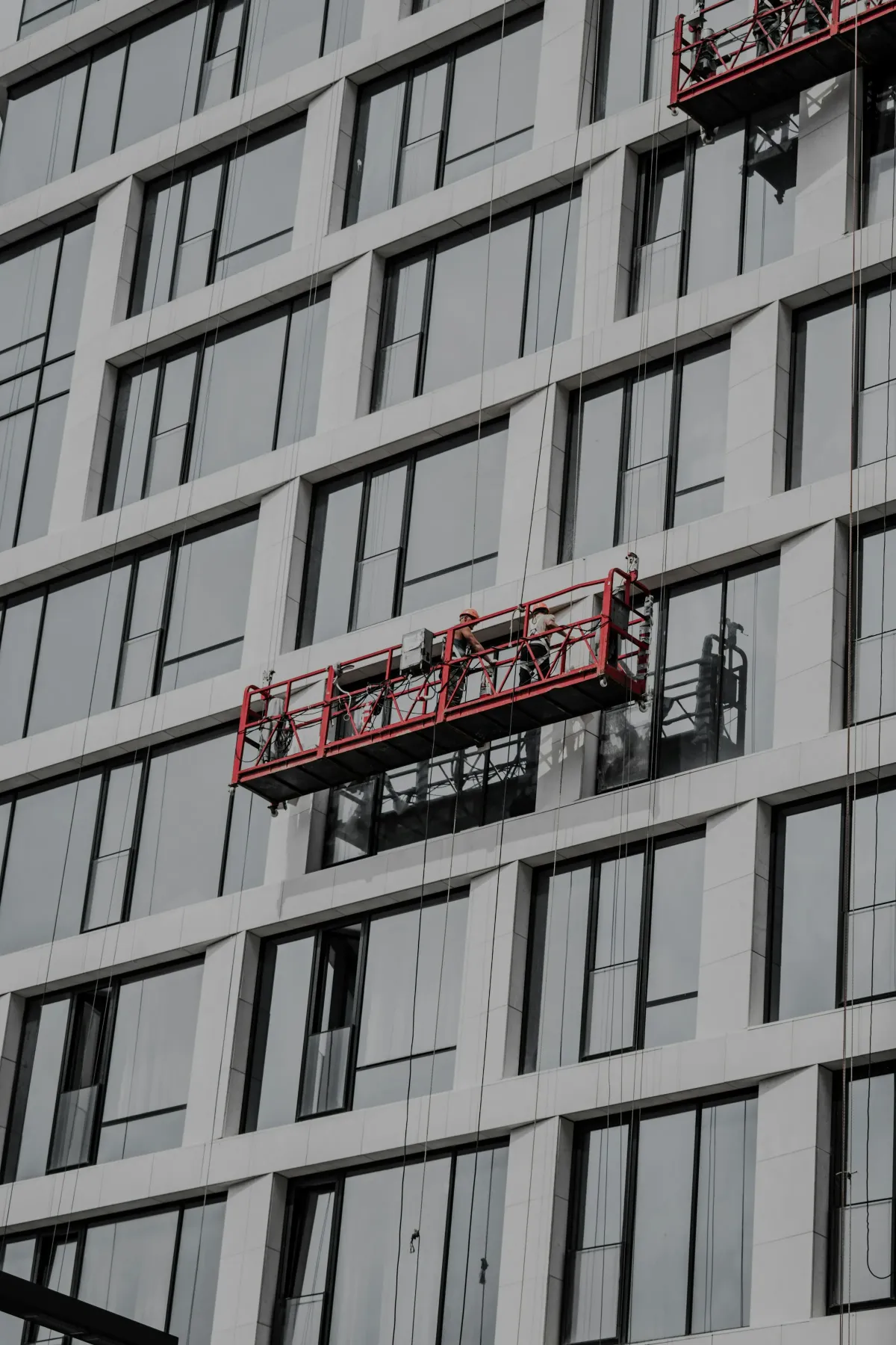 Window cleaners on a BMU cradle platform on the outside of a hotel