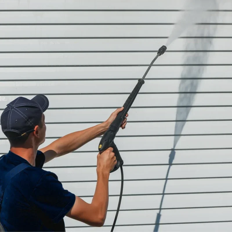 Man pressure washing cladding facade