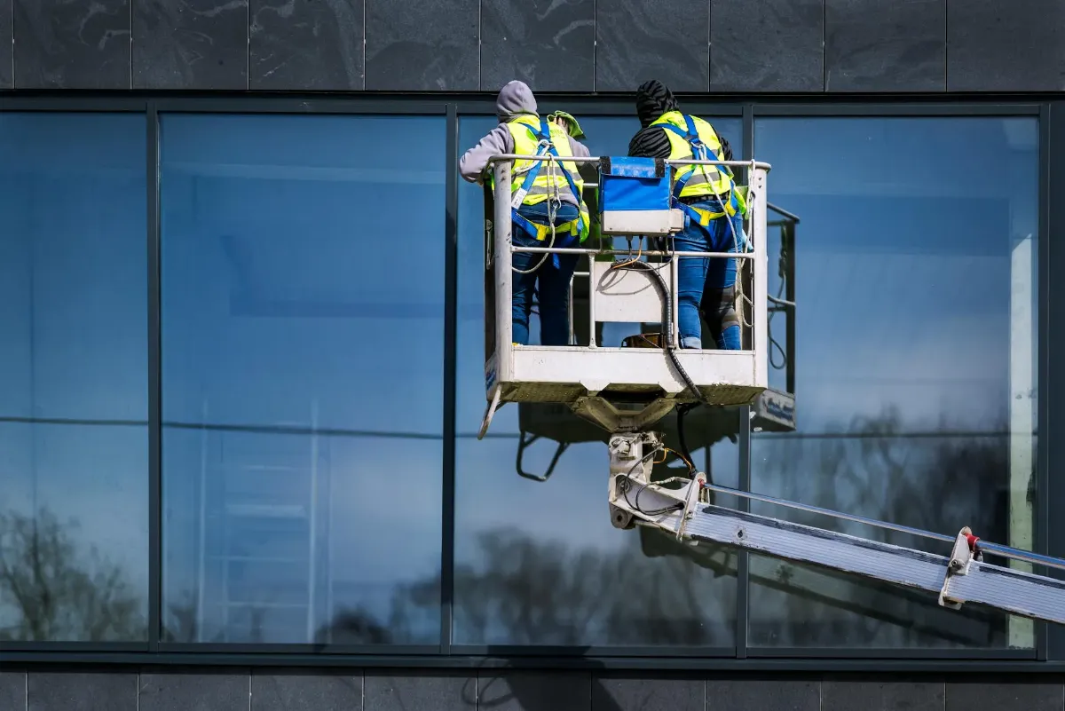 window cleaners cleaning a building's glass windows from a Mewps elevated platform