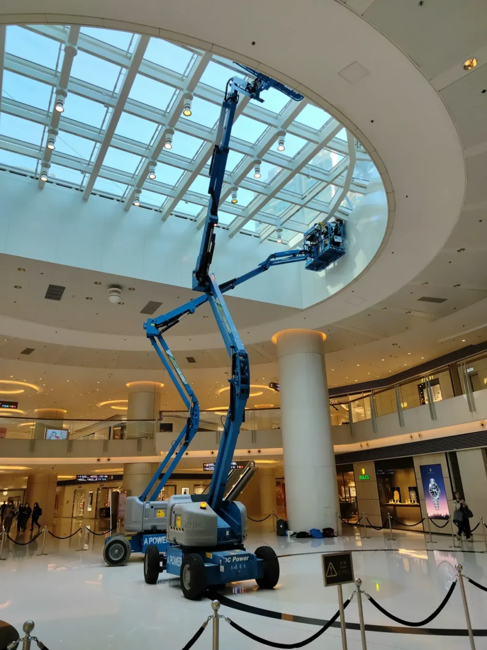 Window Cleaners using cherry pickers to access and clean high window inside a shopping centre