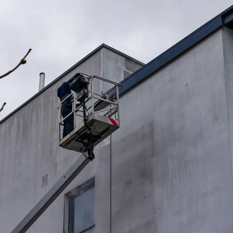 a facade cleaner in a cherry picker cleaning a building's exterior