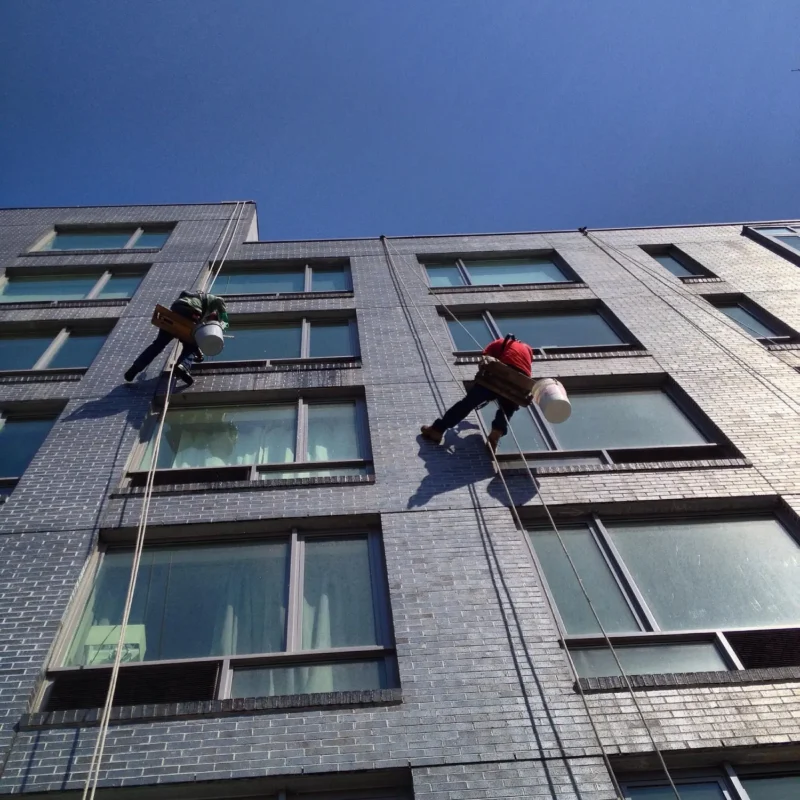 professional window cleaners suspended on ropes washing the windows of a hotel