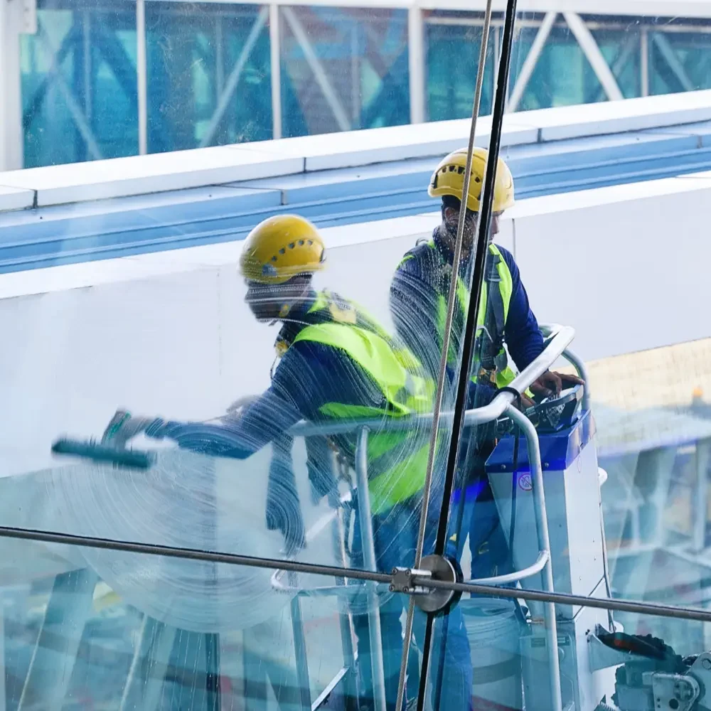 professional window cleaners applying soap and squeegee to the external glass of a large hotel building in London Kensington