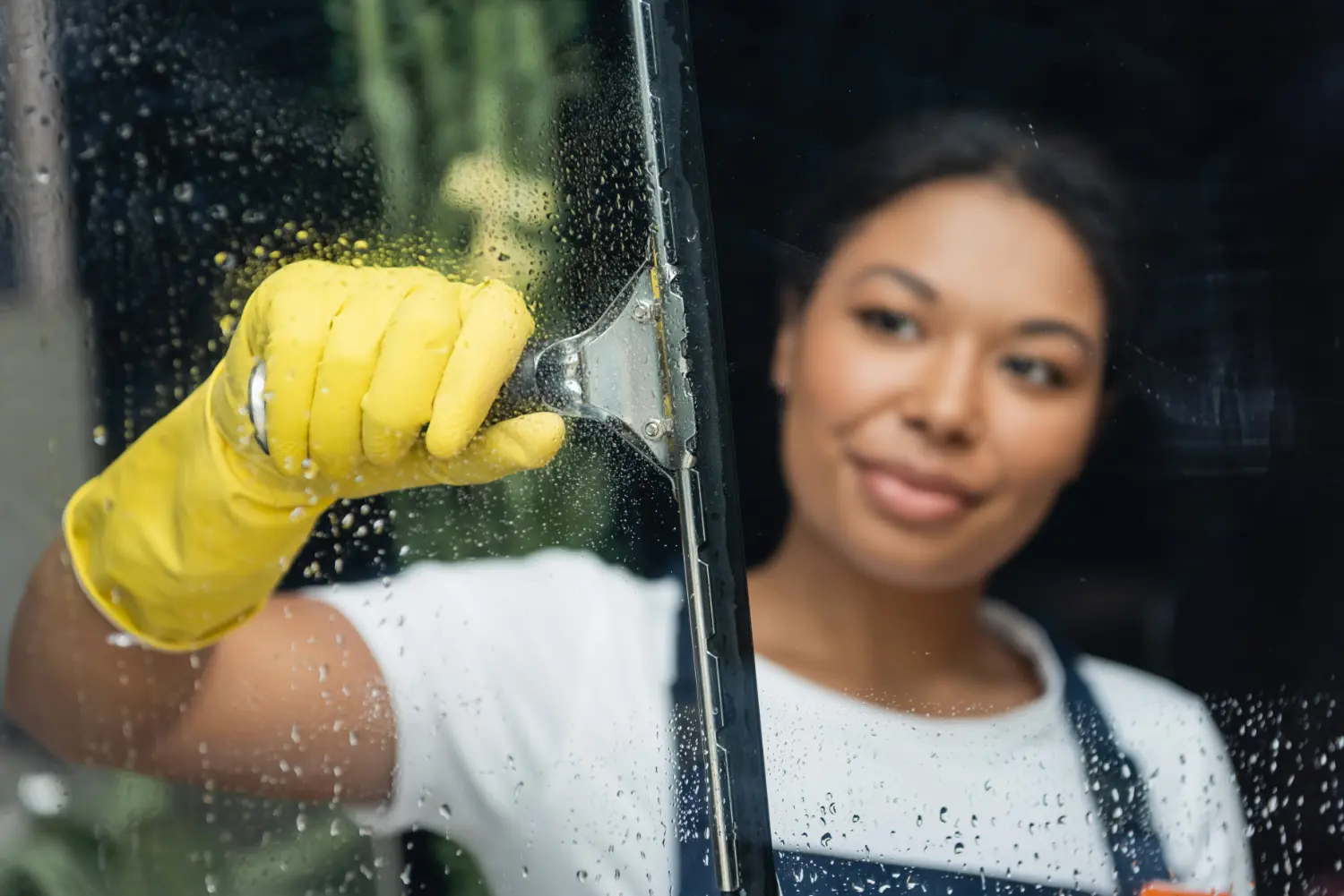 a window cleaner cleaning a hotel guest room interior window using the traditional method