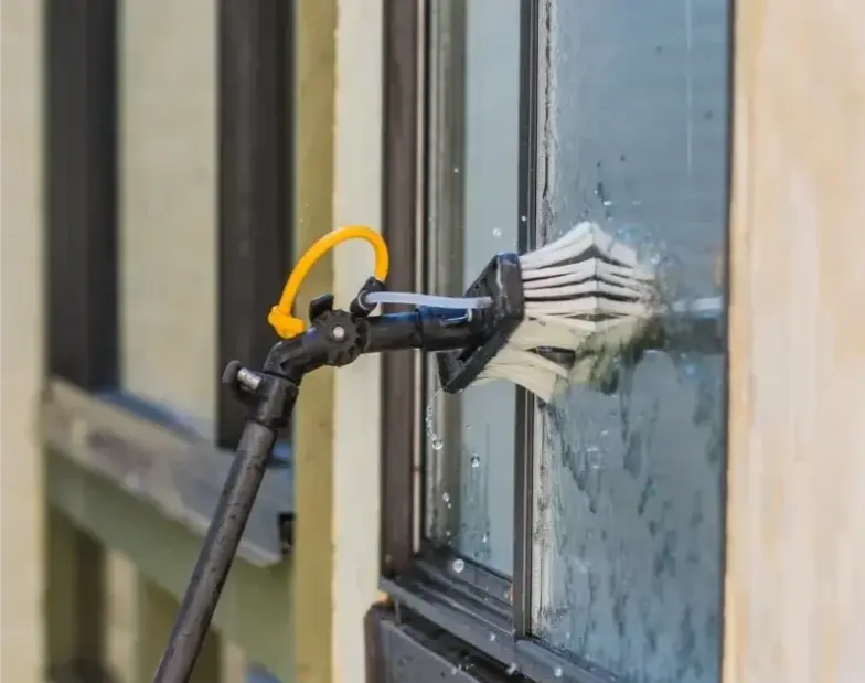 Saval UK technician using a water-fed pole to clean ground-floor windows on a London office building
