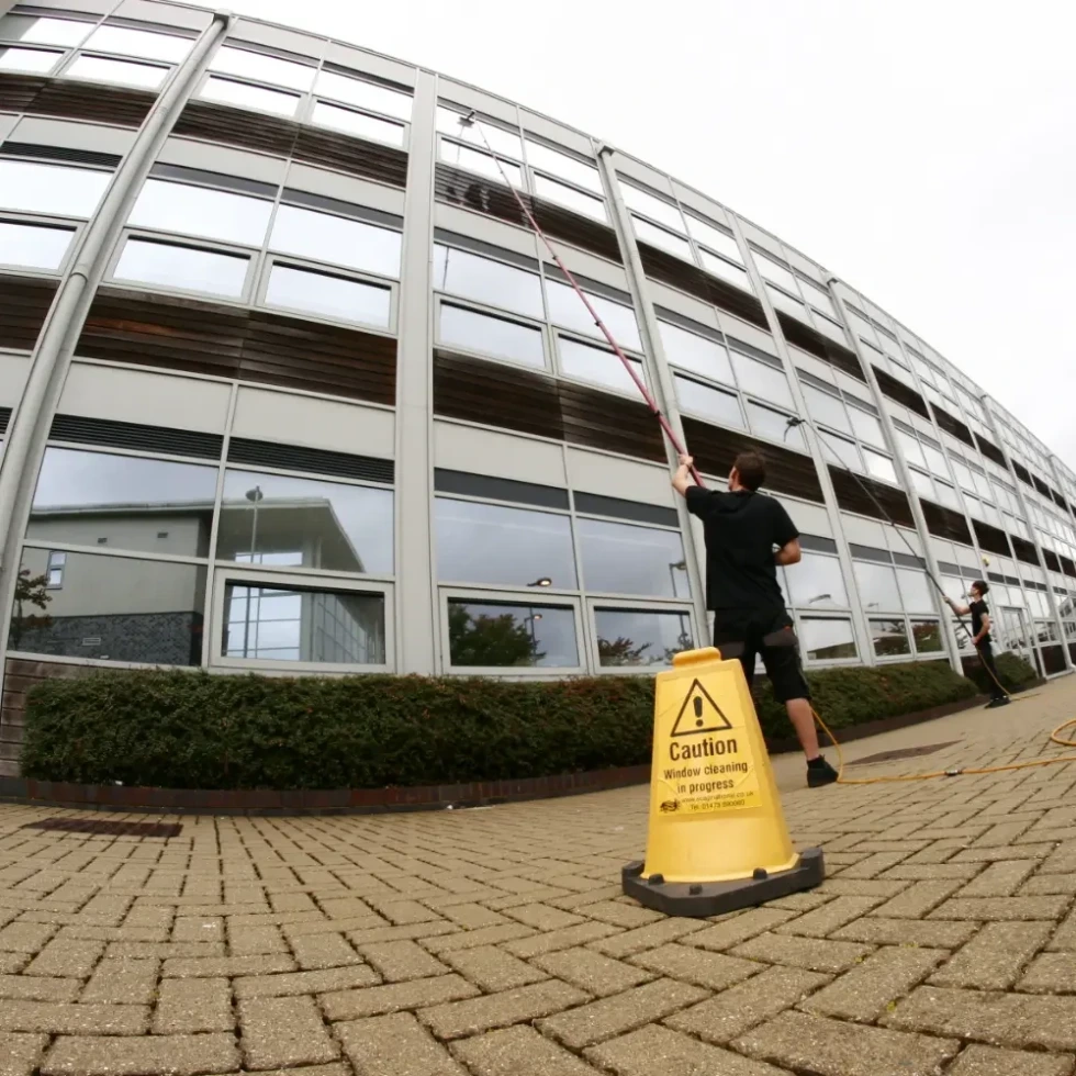 a team of window cleaners using pure water reach and wash equipment to clean a school building's windows