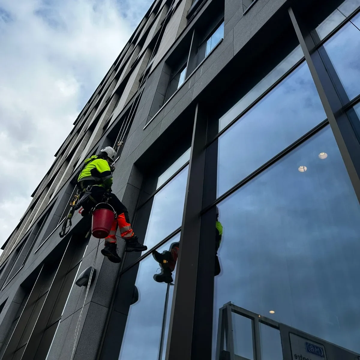 Abseiler from Saval UK cleaning the upper-floor windows of a high-rise London building